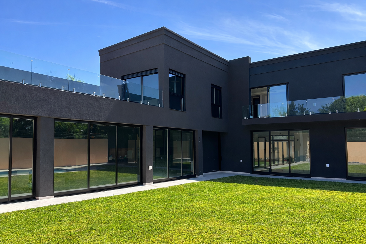 Casa moderna con grandes ventanales de aluminio negro y barandas de vidrio